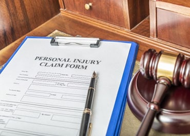 Personal injury claim form on clipboard with judge's gavel - The Law Office Of Fred A Medina PLLC