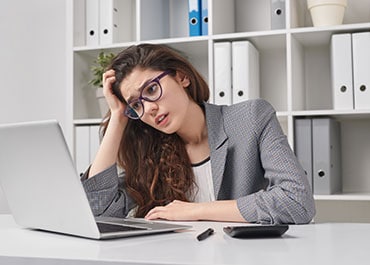 A stressed woman with a concerned expression looking at a laptop, illustrating the concept of Pitfalls of Probate.